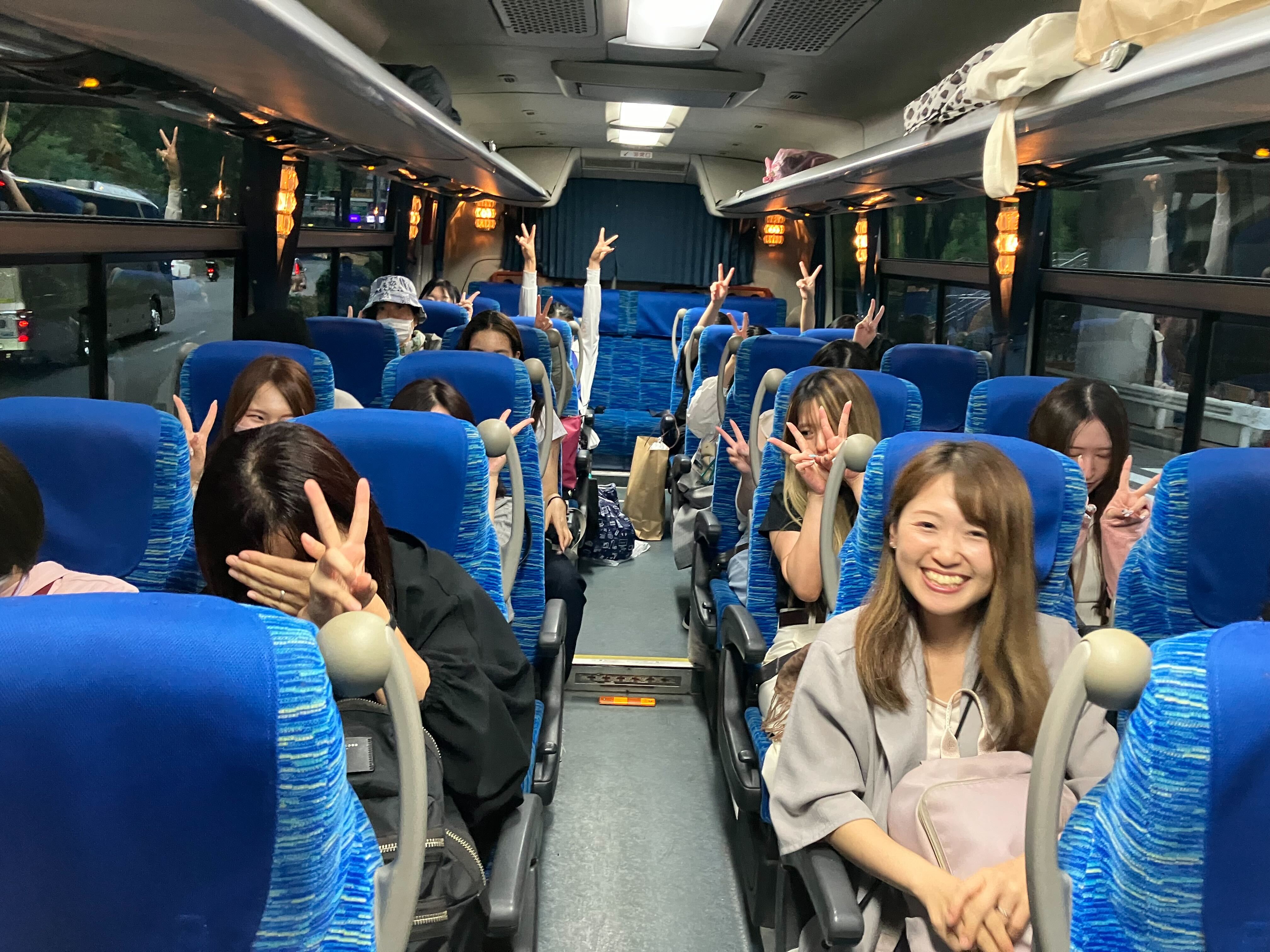 イベント当日の様子。バスの車内で微笑んだりピースしたりして賑やかそうな参加者たちの様子。